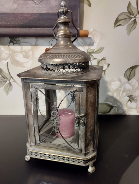 Vacker lykta som passar perfekt för att skapa en romantisk och mysig stämning i ditt hem.  Hållare för värmeljus följer med.  Mått: 22x50cm  Färg: Antik Brun  Material: Metall/Glas