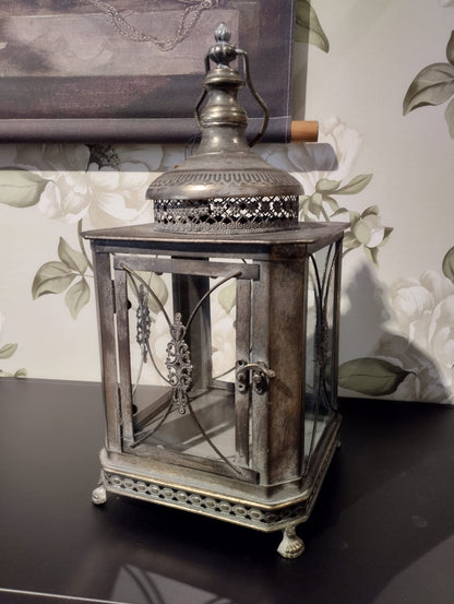 Vacker lykta som passar perfekt för att skapa en romantisk och mysig stämning i ditt hem.  Hållare för värmeljus följer med.  Mått: 22x50cm  Färg: Antik Brun  Material: Metall/Glas