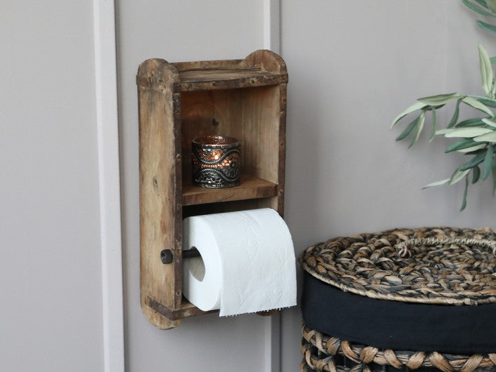 Rustik toalettpappershållare som är tillverkad av en gammal murstensform. Det finns en liten hylla. Passar bra för en vanlig toalettpappersrulle.  Mått: H 30cm, L 15cm, B 10cm  Material: Trä. OBS: Detta är en unik produkt, storlek och utseende kan variera lite. Metallbeslag kan fattas vilket gör att de ser naturligt slitna ut. Det kan även förekomma sprickor i träskivorna.