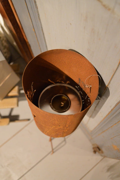 Marschallhållare med utskurna löv på båda sidor, med delbar stav och markfäste. Går utmärkt att sätta en blomma i den också.  Material: Rostig plåt  Storlek: ca 12 x 17 x 114 cm  OBS: Ljus ingår ej. Staven och hållare skruvas ihop.